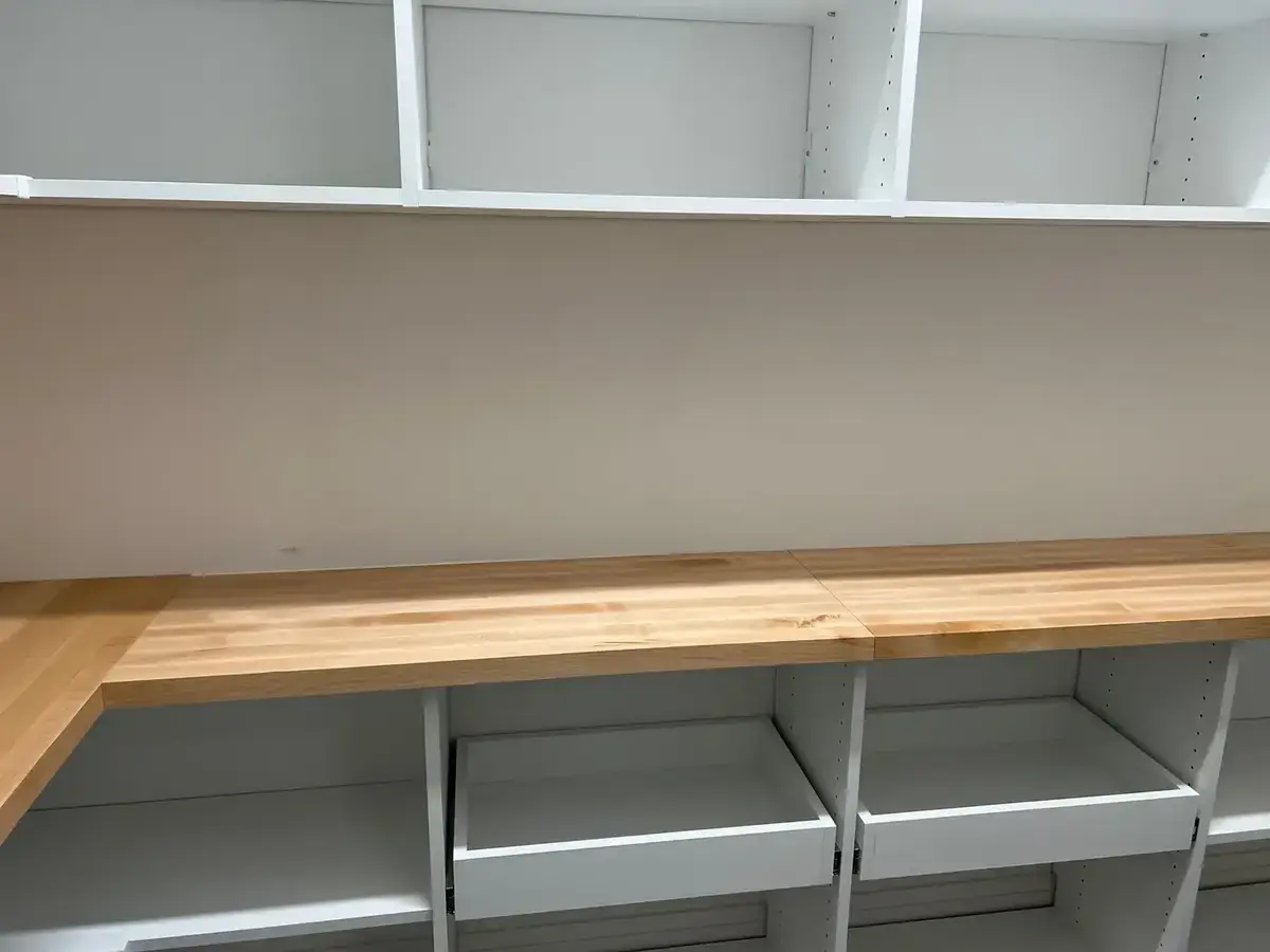 Custom garage with butcher-block workbench, white cabinets and open shelving