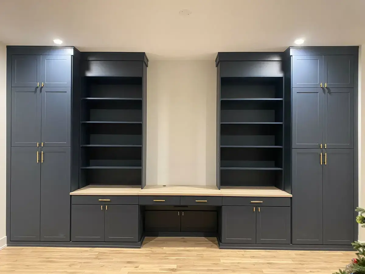 Floor-to-ceiling navy built-in office wall with gold hardware and custom desk surface